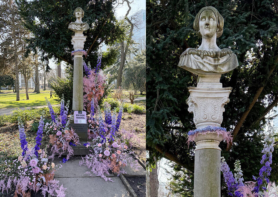 Stephanie-von-Portugal-Statue in Düsseldorf blumig dekoriert zum Frauentag Statue von Stephanie von Portugal in Düsseldorf, feierlich mit bunten Blumenarrangements in Lila, Rosa und Weiß geschmückt.