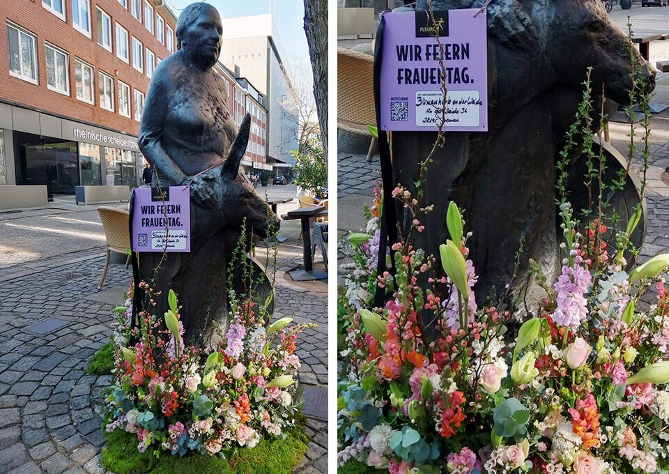 Mudder-Cordes-Statue in Bremen mit Blumenarrangements zum Frauentag Denkmal der Mudder Cordes in Bremen, geschmückt mit eleganten Blumenarrangements in Rosa, Weiß und Pastelltönen zum Frauentag.