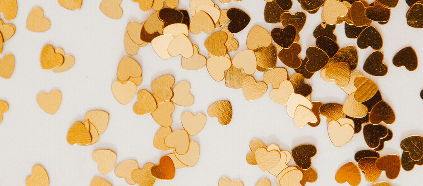 Goldene Herzkonfetti auf hellem Hintergrund zur goldenen Hochzeit