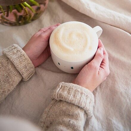 2 Händer umschließen eine mit Kaffee gefüllte Tasse
