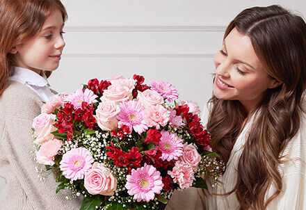 Mutter und Tochter freuen sich über einen großen rosa Blumenstrauß.