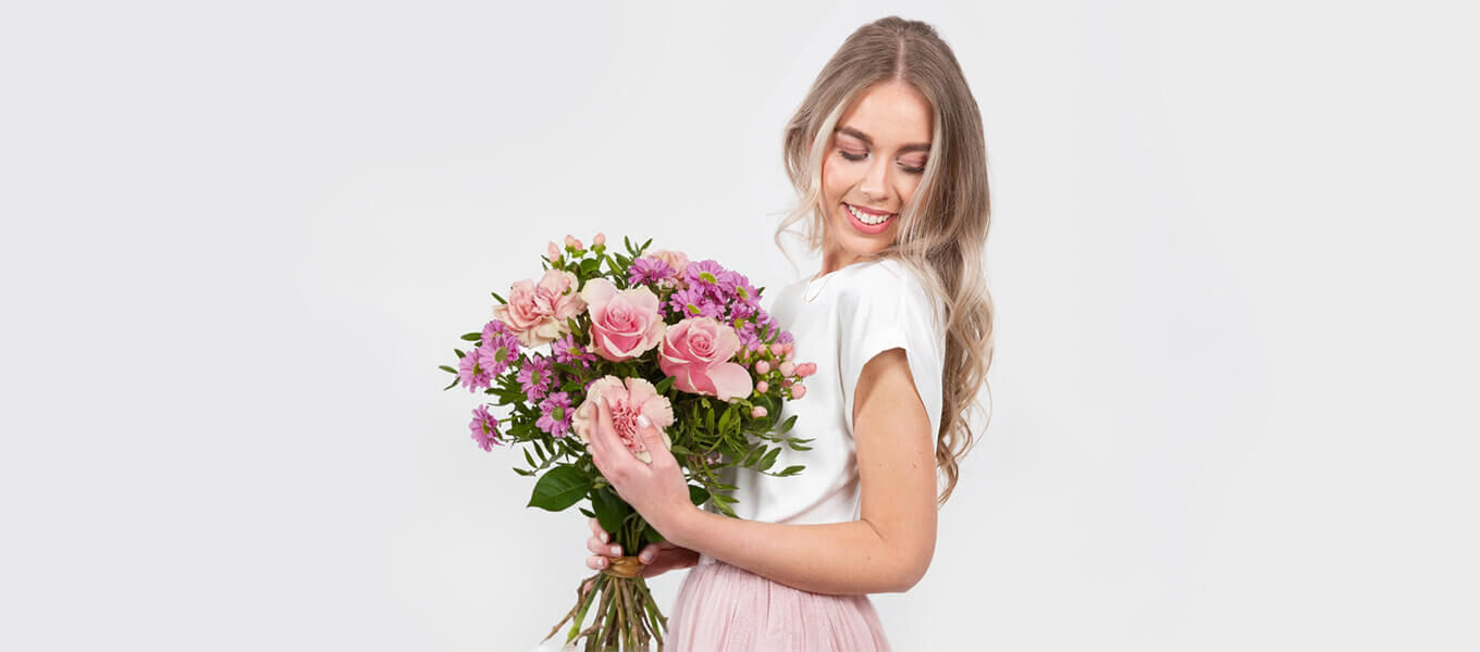 Frau hält einen rosa Blumenstrauß als Zeichen von Freundschaft und Dankbarkeit