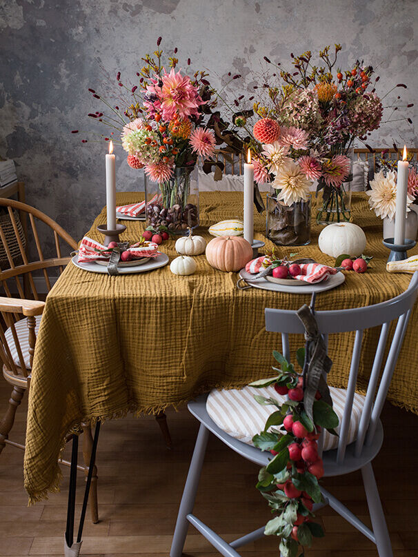 Festlich gedeckter Herbsttisch mit Dahlien, Kürbissen und Kerzen