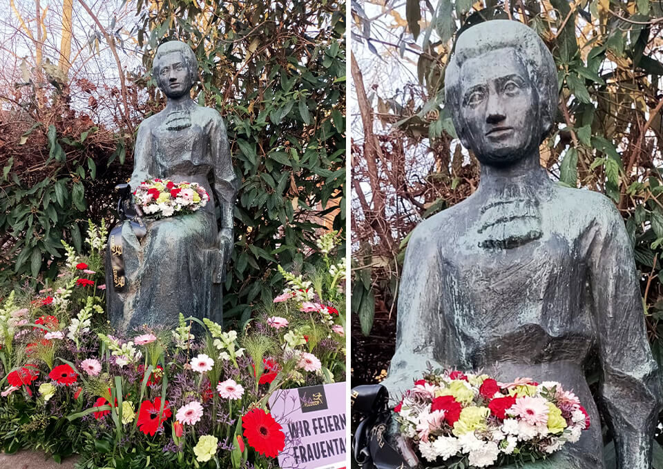Statue von Rosa Luxemburg in Erfurt, mit farbenfrohem Blumenstrauß aus roten und weißen Blüten dekoriert zum Frauentag.