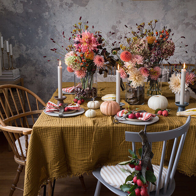 Festlich gedeckter Herbsttisch mit Dahlien, Kürbissen und Kerzenlichtern