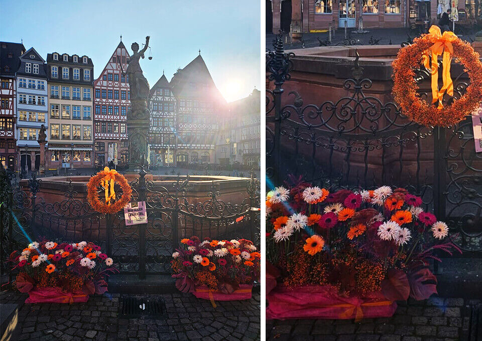Gerechtigkeitsbrunnen in Frankfurt mit Blumenarrangements zum Frauentag Justitia-Statue am Gerechtigkeitsbrunnen in Frankfurt, mit leuchtenden Gerbera und einem orangefarbenen Blumenkranz geschmückt.