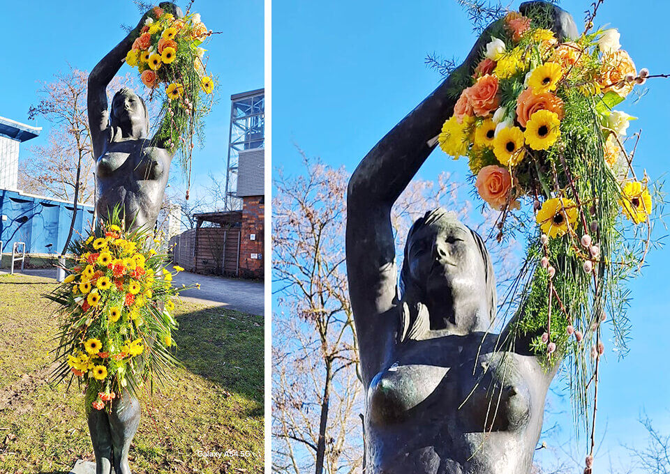 Statue „Sportstudentin Sonja“ in Potsdam mit Blumen geschmückt zum Frauentag Bronzefigur einer Sportstudentin in Potsdam, kunstvoll mit gelben Gerbera, Rosen und frischen Blütenarrangements zum Frauentag dekoriert.
