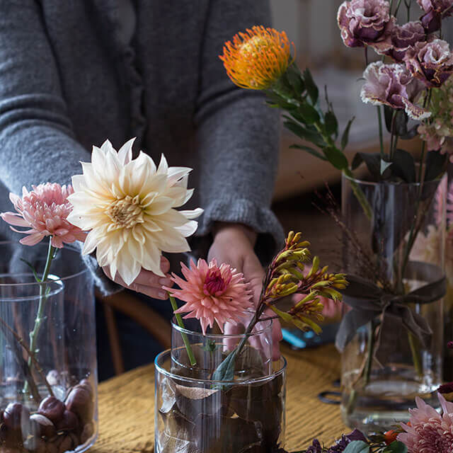 Dahlien in einer Glasvase mit Herbstlaub dekorieren