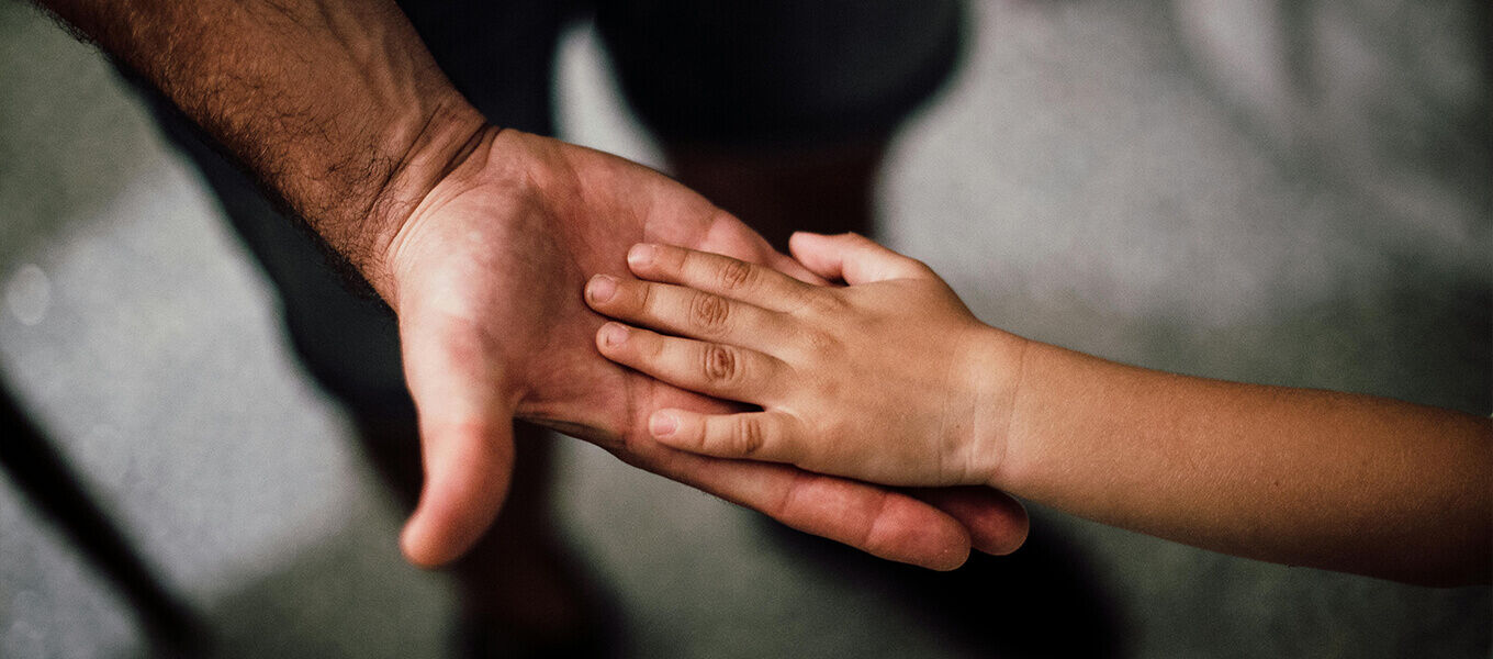Glückwünsche zum Vatertag – die schönsten Ideen für Deinen Papa Kinderhand liegt liebevoll in der geöffneten Hand eines Vaters – Symbol für Vertrauen, Nähe und die besondere Vater-Kind-Bindung.