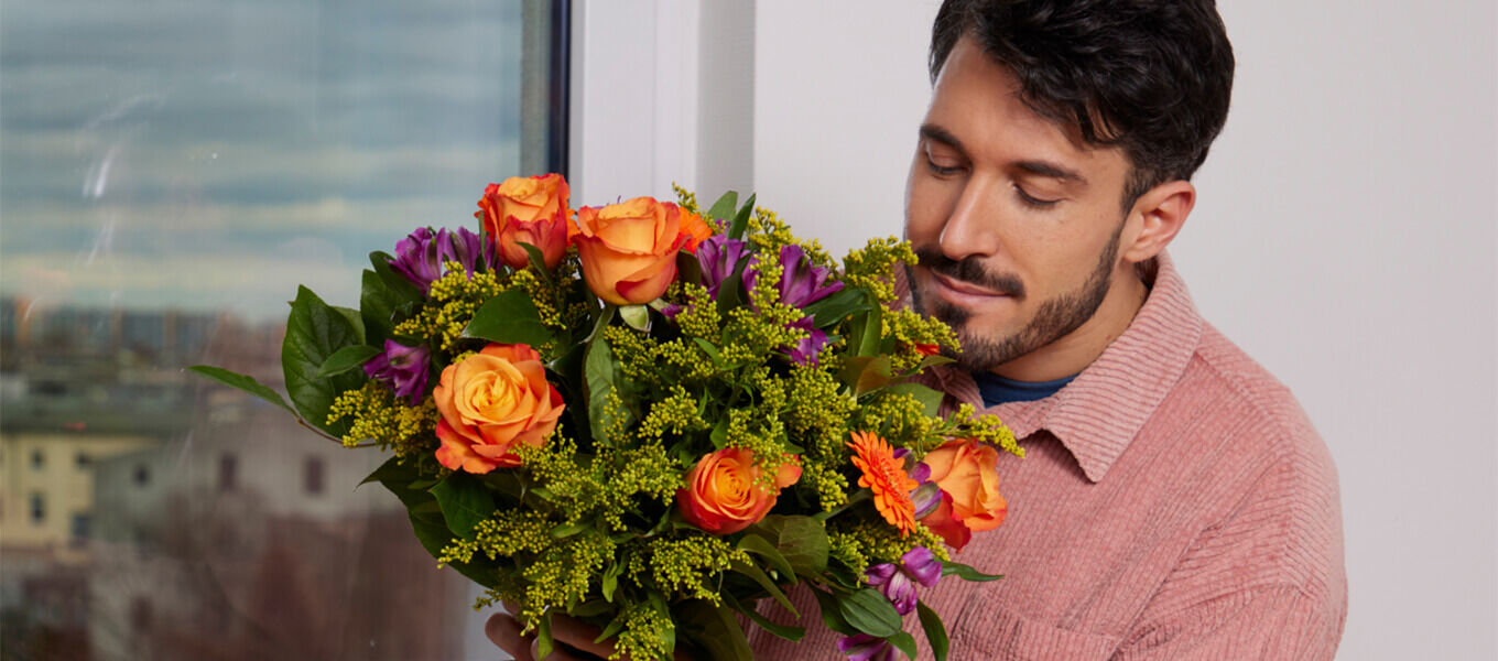 Mann mit buntem Blumenstrauß als Geburtstagsgeschenk