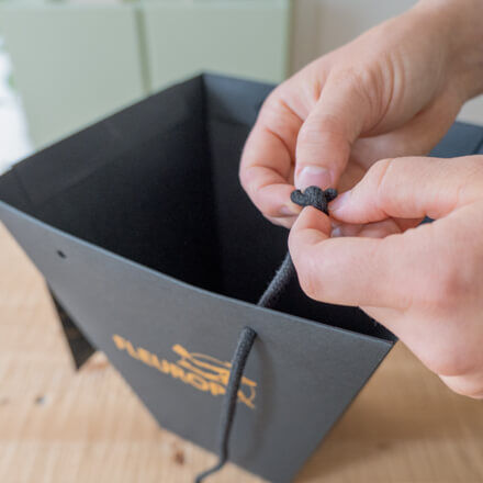Die schwarzen Henkel einer Flowerbag werden von zwei Händen entfernt.
