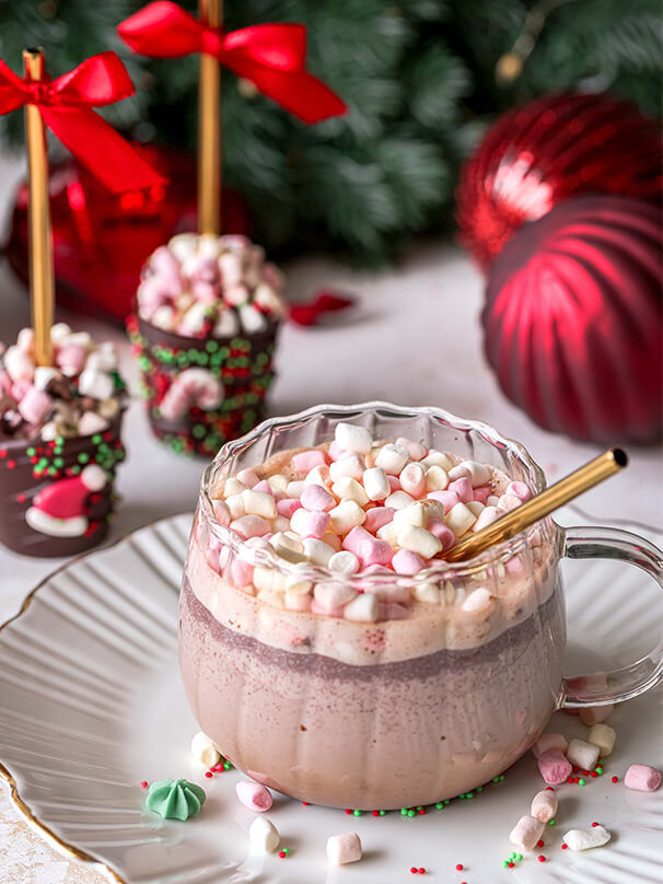 Heiße Schokolade mit geschmolzener Schokolade und Mini-Marshmallows, serviert in einer durchsichtigen Tasse mit goldenem Strohhalm.