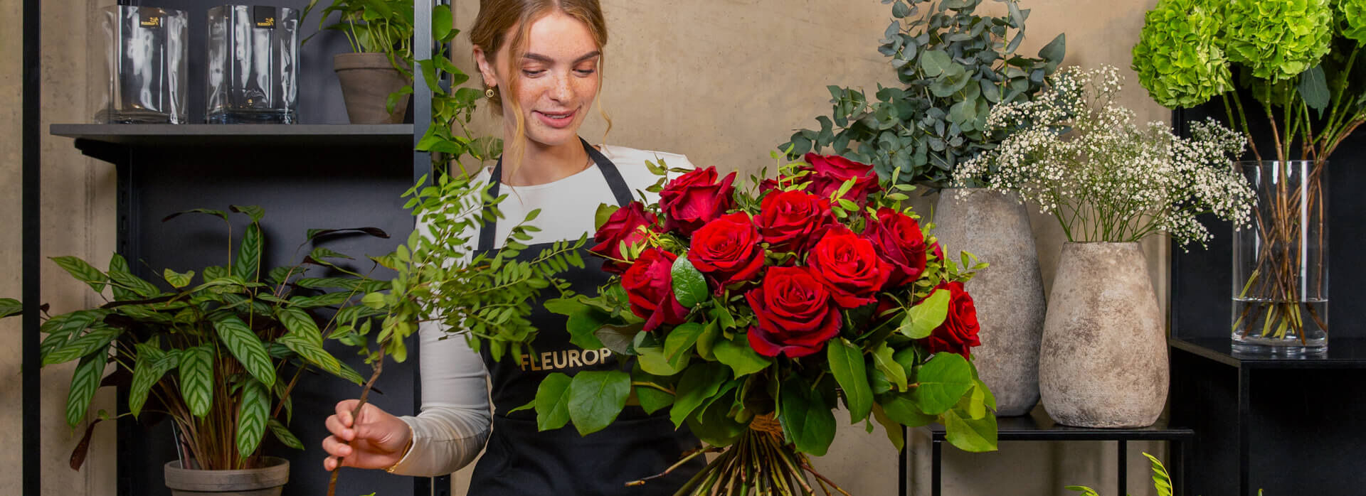 Florist beim Arrangieren eines Straußes roter Rosen