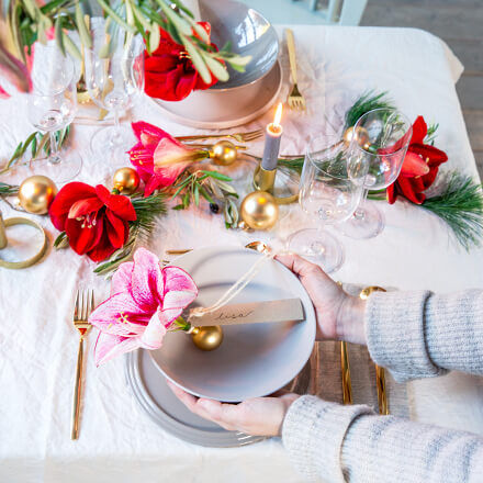 Tischdekoration: Eine pinke Amaryllisblüte in eine Weihnachtskugel gesteckt und mit einem Namensschild dran.
