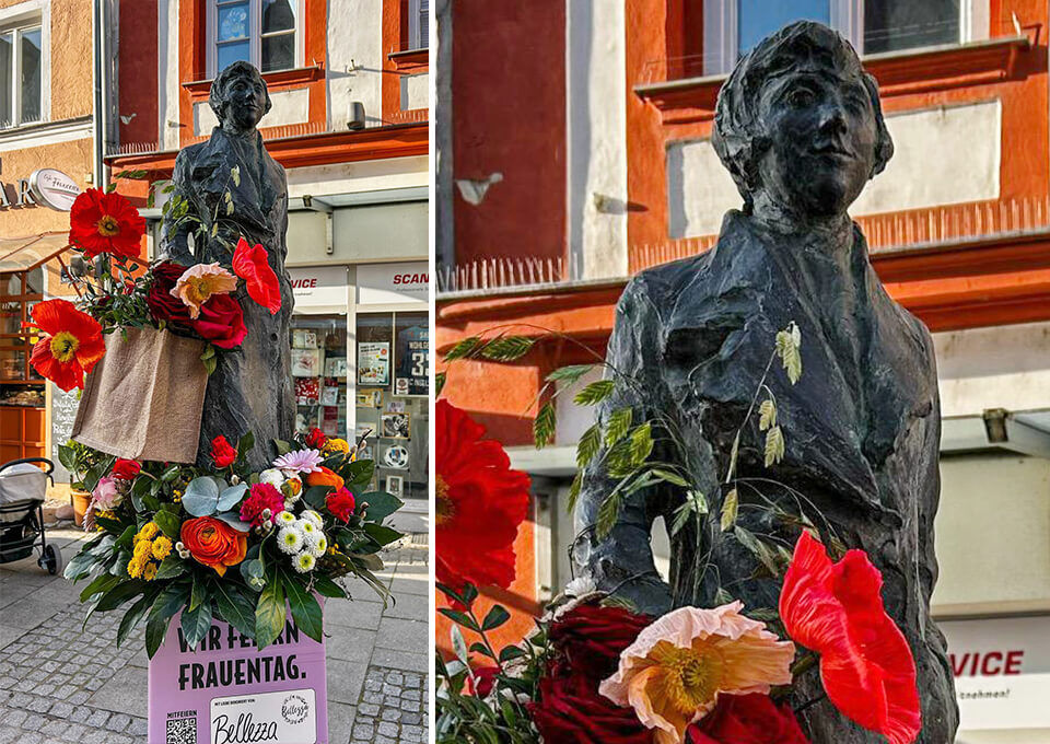 Statue von Marieluise Fleißer in Ingolstadt, festlich mit roten Mohnblumen, Rosen und bunten Sträußen geschmückt zum Frauentag.