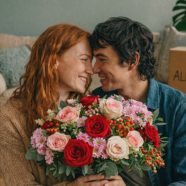Happy couple with a bouquet of flowers as they move into their new home
