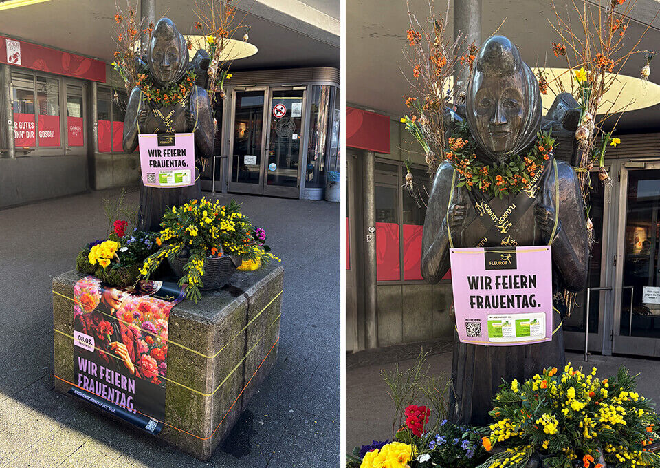 Marktfrau in Hannover blumig geschmückt zum Frauentag Statue der Marktfrau in Hannover, dekoriert mit leuchtenden Frühlingsblumen in Gelb, Orange und Grün zum Weltfrauentag.