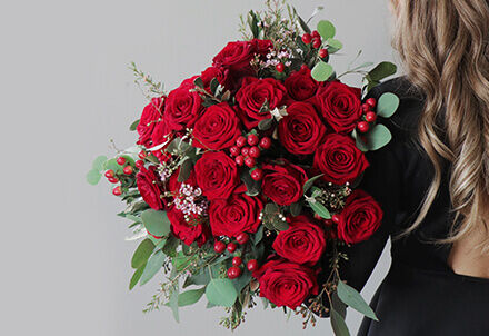 Frau mit rotem Rosenstrauß als Geschenkidee zum Hochzeitstag