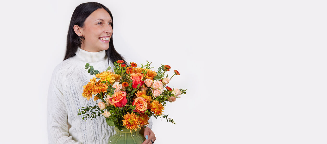 Frau mit orangefarbenem und rosafarbenem Blumenstrauß als liebevolle Aufmerksamkeit ohne Anlass