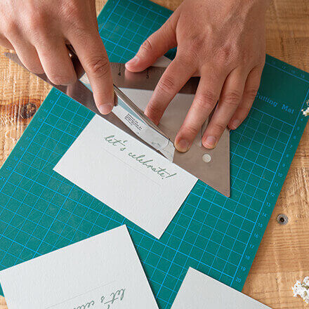 Der Ausdruck der Hochzeitskarte wird an zwei gegenüberliegenden Streifen mithilfe eines Cuttermessers eingeschnitten
