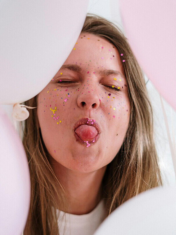 Witzige Geburtstagswünsche – Frau mit Konfetti im Gesicht macht lustiges Gesicht