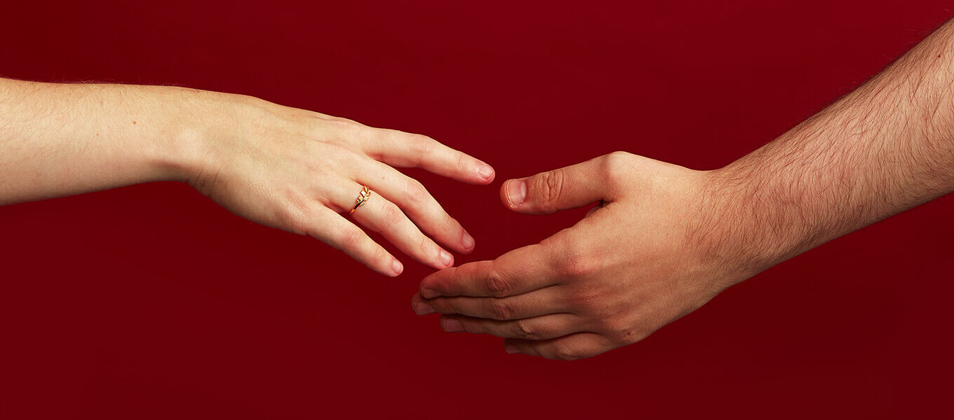 zwei Hände die nach einander greifen vor rotem Hintergrund