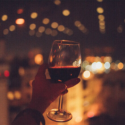 Hand hält Weinglas mit Rotwein