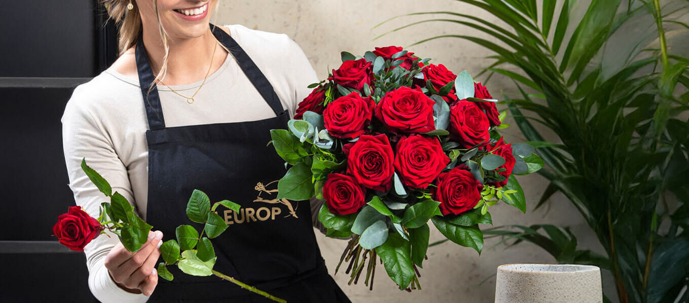 Florist, der einen Strauß in Rot-Pink bindet