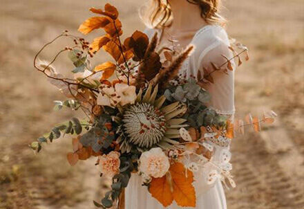 Natürlicher Hochzeitsstrauß mit Herbstblumen wie Protea, Nelken und Herbstästen