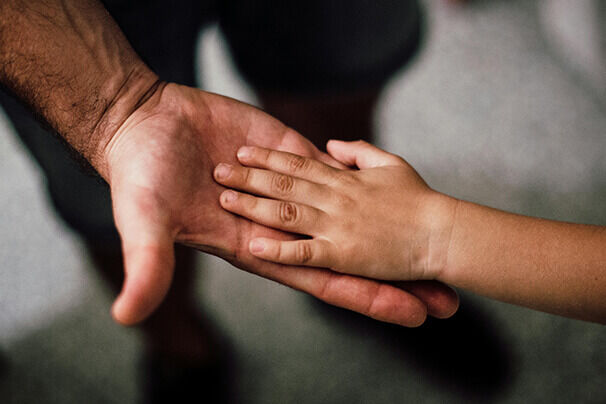 Kinderhand liegt liebevoll in der geöffneten Hand eines Vaters – Symbol für Vertrauen, Nähe und die besondere Vater-Kind-Bindung.